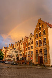 Buildings by road against sky during sunset