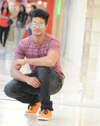 Portrait of young man crouching on floor at shopping mall