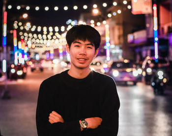 Portrait of a smiling young man standing in city at night