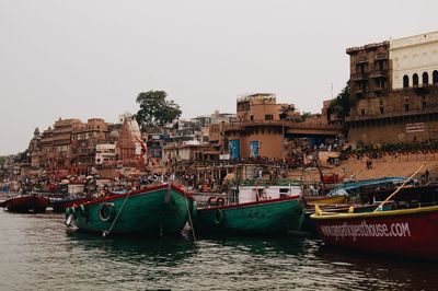 Boats moored in sea against buildings in city