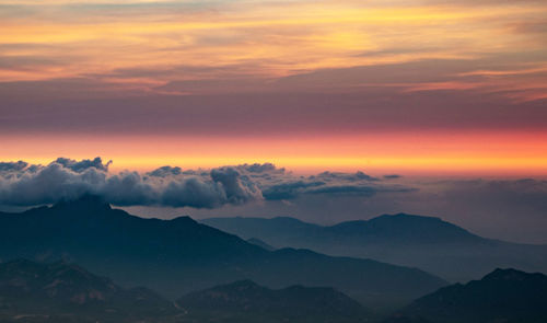 Scenic view of mountains against dramatic sky during sunset