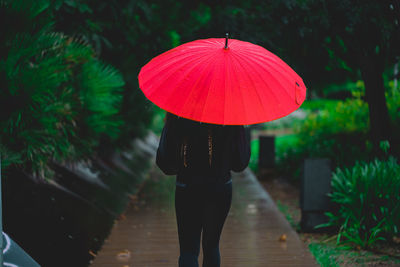 Woman walks through a park with a red umbrella in palma, spaim