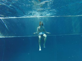 Shirtless man swimming underwater