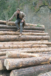 Young man standing on logs in forest