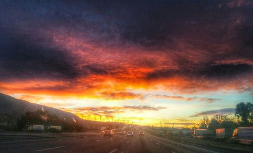 Scenic view of road against cloudy sky during sunset