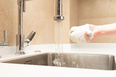 Cropped hand washing hands in sink