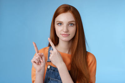 Redhead woman gesturing against blue background