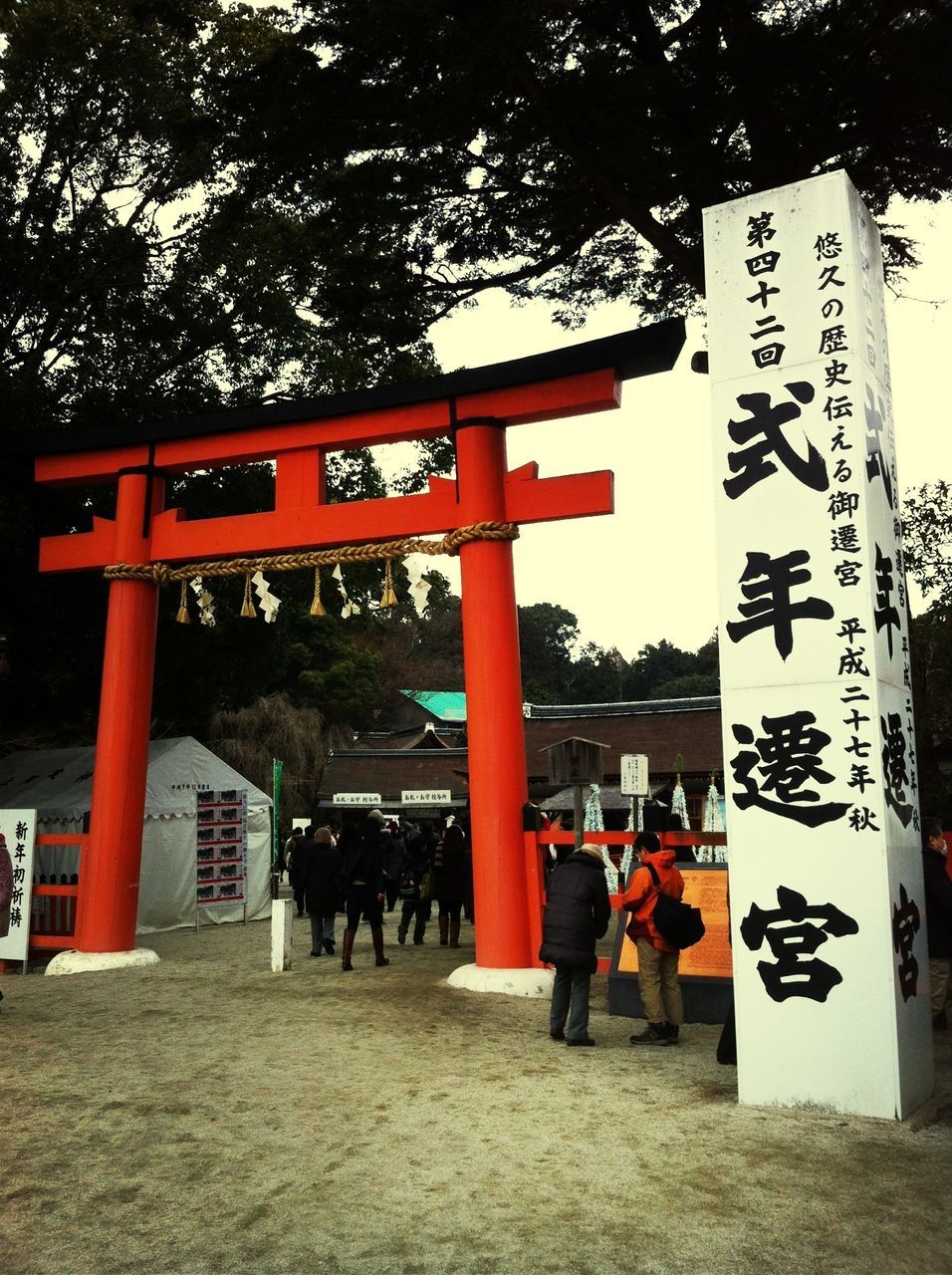 tree, text, western script, built structure, communication, architecture, building exterior, non-western script, day, sign, outdoors, men, sunlight, person, sky, information sign, wood - material, lifestyles, city