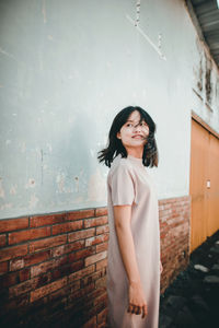 Portrait of young woman standing against wall