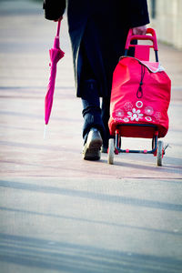 Low section of man with luggage walking on footpath