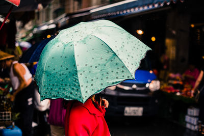 Rear view of woman holding umbrella during rainy season