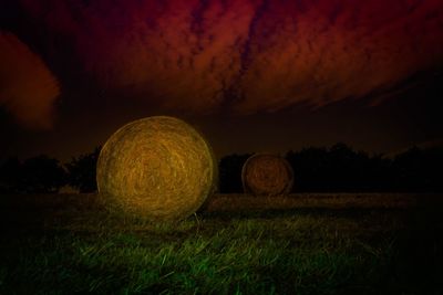 Hay bales on field against sky at night
