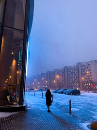 Rear view of man on illuminated street in city at night