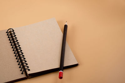 High angle view of pencil and spiral notebook on beige background