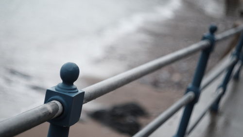 Close-up of metal railing against water
