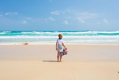 Rear view of woman on beach against sky