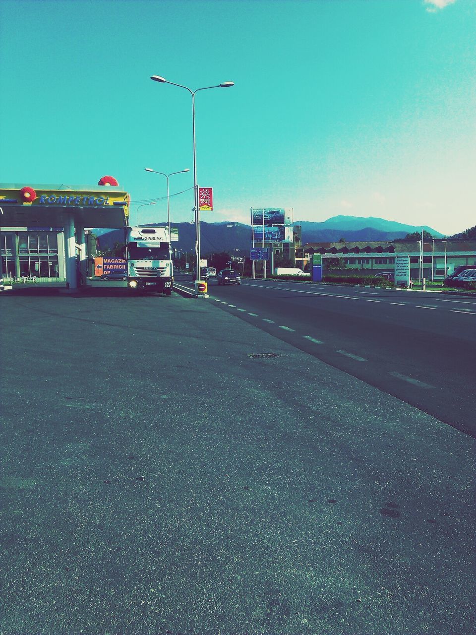 transportation, clear sky, road, mode of transport, land vehicle, street light, street, car, building exterior, copy space, road marking, architecture, built structure, the way forward, sky, blue, illuminated, city, empty, asphalt