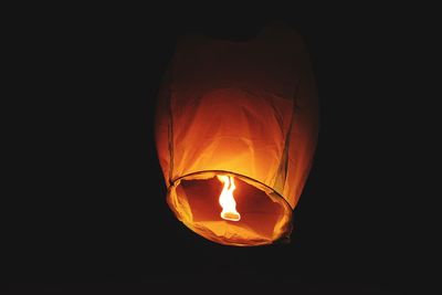 Low angle view of illuminated lantern against black background