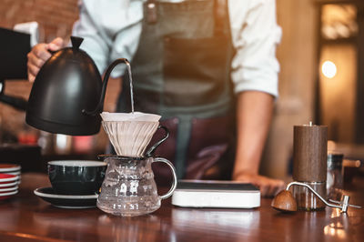 Midsection of man holding coffee cup on table