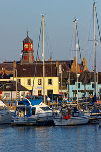 Sailboats moored at harbor against clear sky