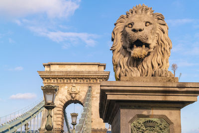 The chain bridge with the stone lion on its entrance with blue sky