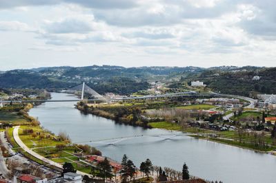 Bridge over river by city against sky