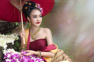 Portrait of beautiful young woman with umbrella looking away