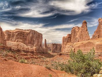 View of rock formations in desert against cloudy sky