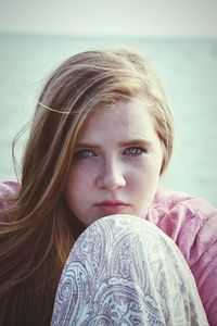 Portrait of young woman leaning on her knee against sea