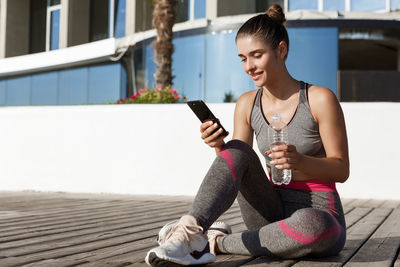 Young woman using mobile phone while sitting on camera