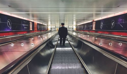 Rear view of man on escalator in airport