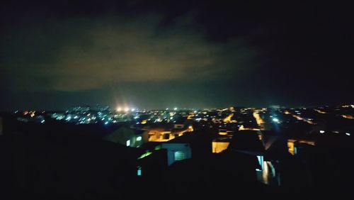 Illuminated cityscape against sky at night