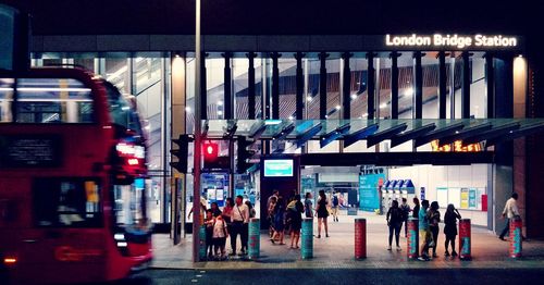 People walking on illuminated street in city at night