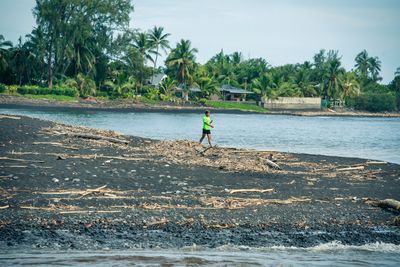 Man walking on shore against trees