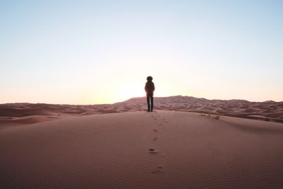 Silhouette man standing on sand dune in sahara desert