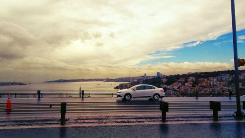 Cars on road against cloudy sky