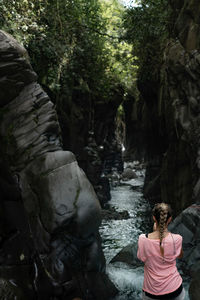 Rear view of man sitting in waterfall