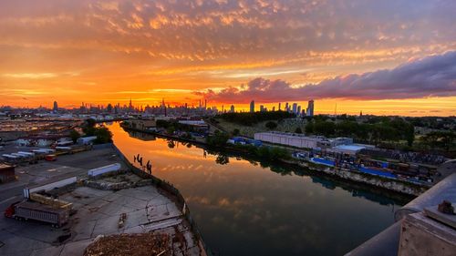 High angle view of river by buildings against sky during sunset