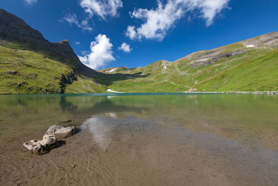 Scenic view of lake by mountains against sky