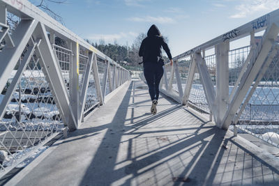 Rear view of man walking on footbridge