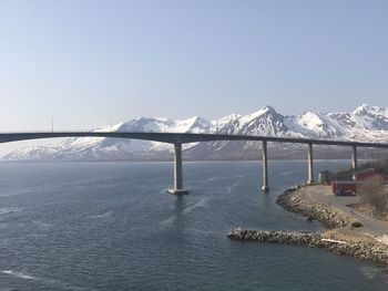 Scenic view of sea by snowcapped mountains against clear sky