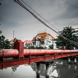 Bridge over river by buildings against sky