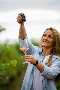 Woman squeezing blueberries in glass at vineyard