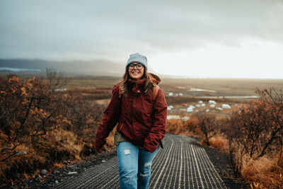 Portrait of young woman standing in winter against sky