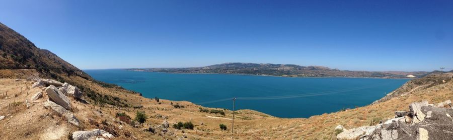 Panoramic view of sea and mountains against clear blue sky