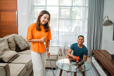 Portrait of young woman using mobile phone while sitting at home