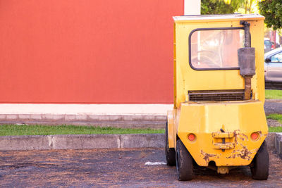 Yellow car on road against wall