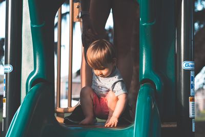 Cute girl sitting on slide in playground
