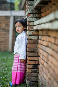 Full length of girl standing by wall at public park