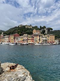 Buildings by sea against sky